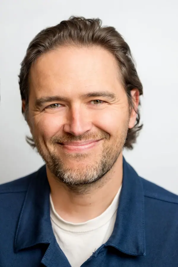 Portrait corporate en studio d'un homme souriant en veste bleue, fond clair