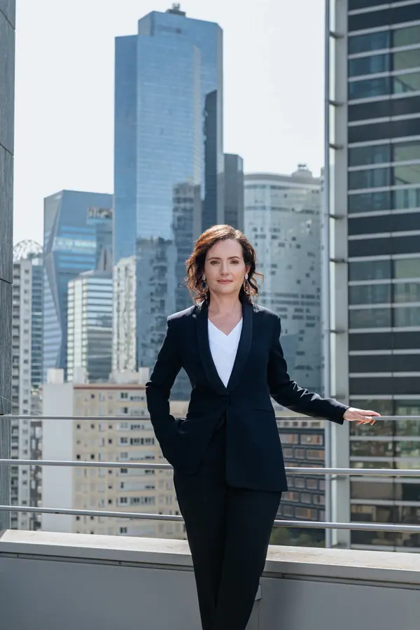 Portrait corporate de Virginie Flam d'IDEMIA en tailleur noir sur un toit, devant des tours de bureaux