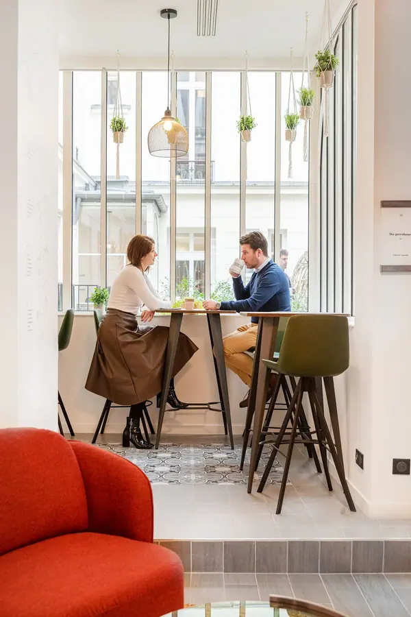 Espace café avec tables hautes et fauteuil rouge sous une verrière, bureaux de Colonies à Paris, architecture intérieure