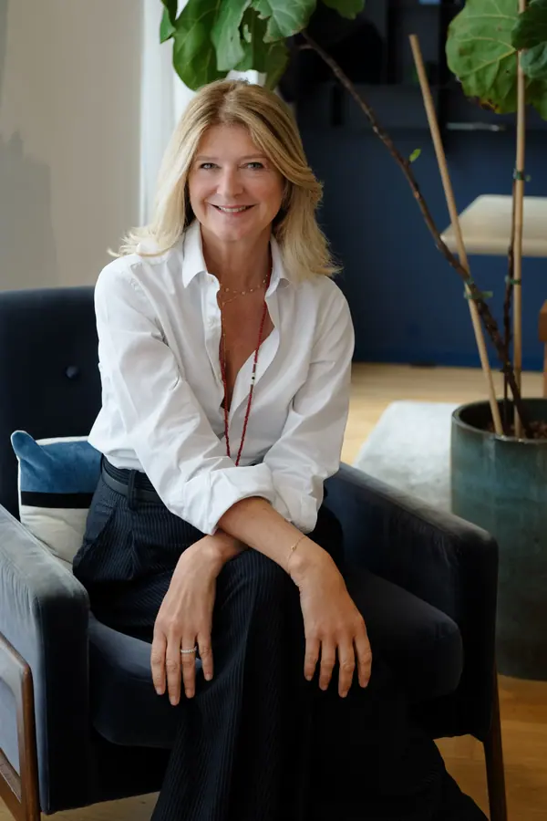 Portrait corporate d'une femme en chemise blanche assise dans un fauteuil bleu, lumière naturelle