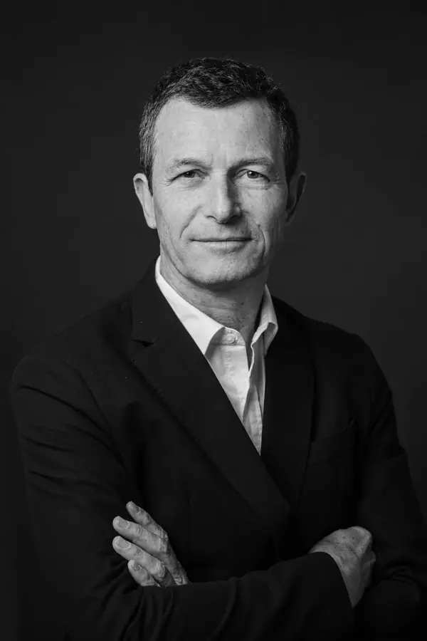 Portrait professionnel noir et blanc d'un associé bras croisés sur fond sombre, photographe pour avocats à Paris