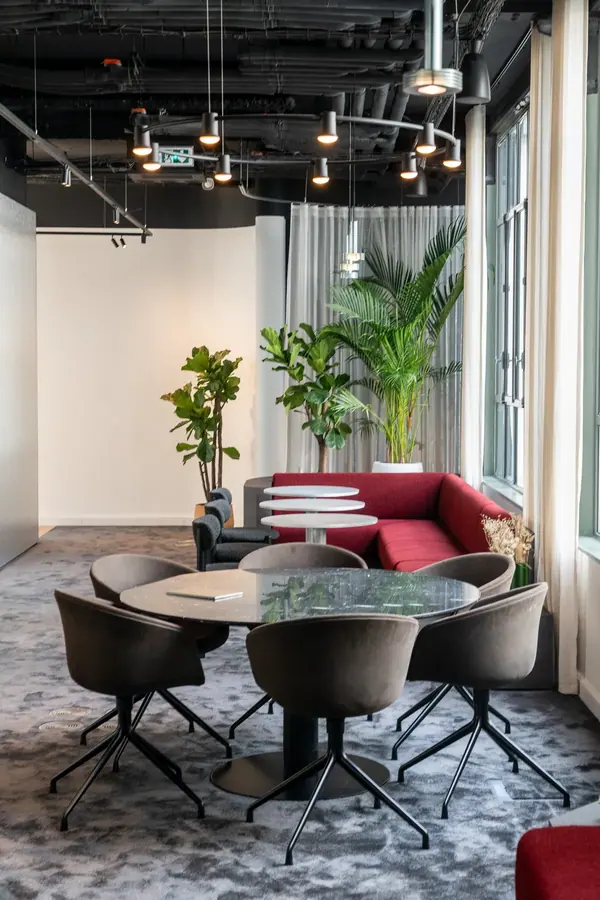 Espace de réunion des bureaux Singular à Paris, table en marbre, fauteuils sombres et plantes, photographie de bureaux