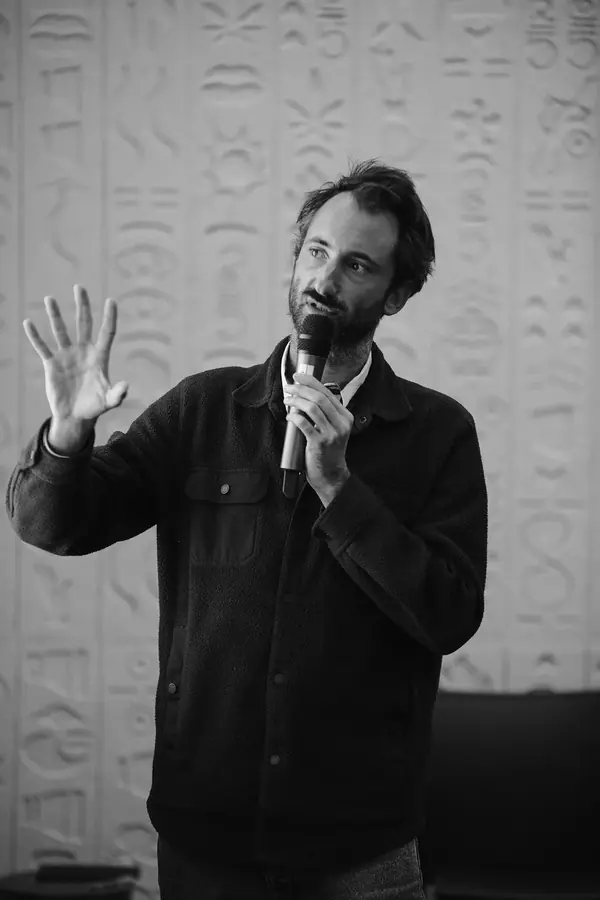 Intervenant au micro devant un mur sculpté lors d'une table ronde Singular à Paris, reportage événementiel