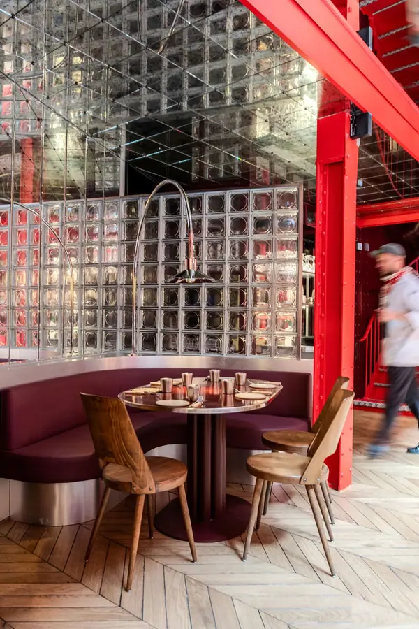 Vue plongeante sur la salle rouge du restaurant Maslow Temple à Paris, banquettes bordeaux et parquet en chevrons
