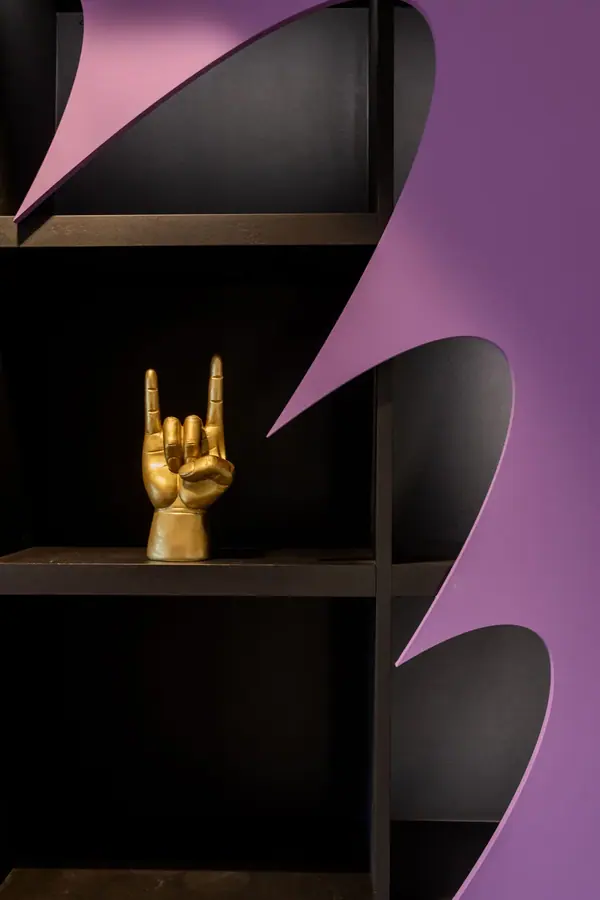 Artist Room de Deezer par Yemanja : étagère noire à découpe violette et sculpture de main dorée, photographie d'intérieur