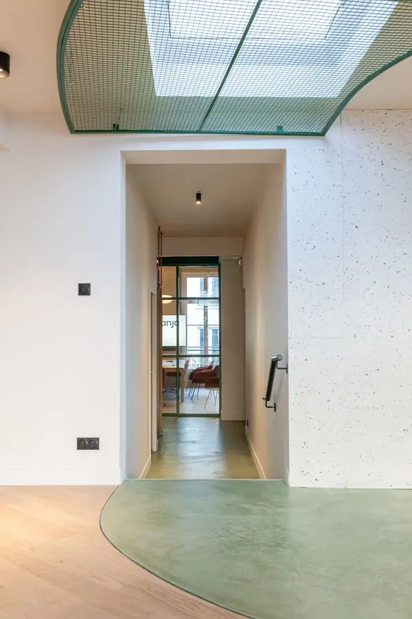 Couloir aux sols verts courbes sous une verrière dans les bureaux Yemanja à Paris, photographie d'architecture intérieure