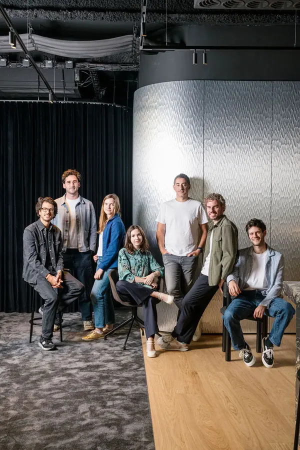 Portrait corporate de groupe de l'équipe Singular assise devant un rideau sombre et un mur métallique