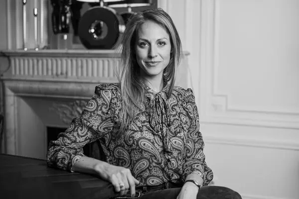 Portrait professionnel de Nathalie assise à une table devant une cheminée en marbre, en lumière naturelle