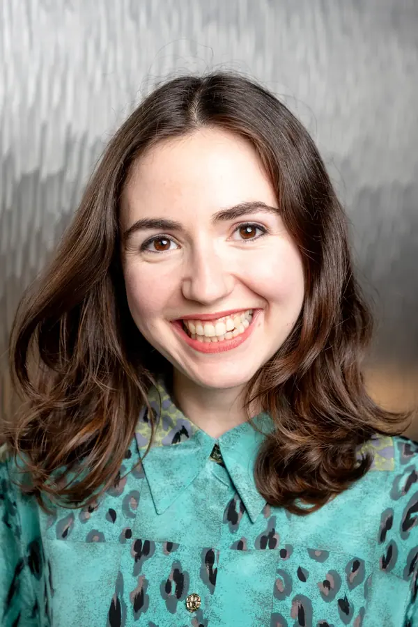 Portrait de collaboratrice souriante devant une paroi métallique, série de portraits d'équipe d'un fonds d'investissement à Paris