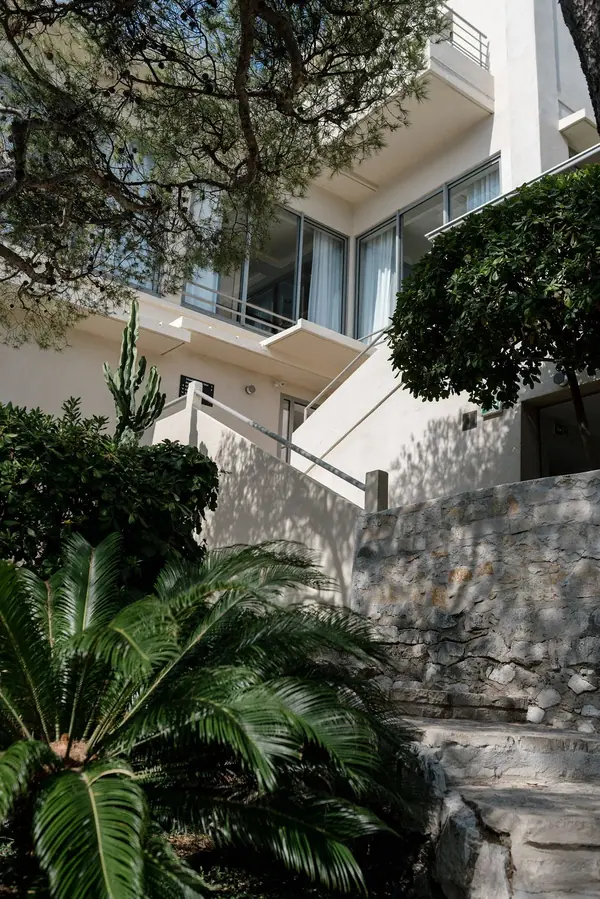 Photographie d'hôtel : façade et terrasses de l'hôtel Les Roches Blanches à Cassis, entre pins et palmiers