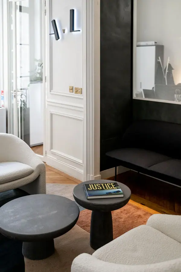 Photographie d'architecture intérieure du Cabinet AL, fauteuils blancs et tables basses sur parquet dans un salon d'attente
