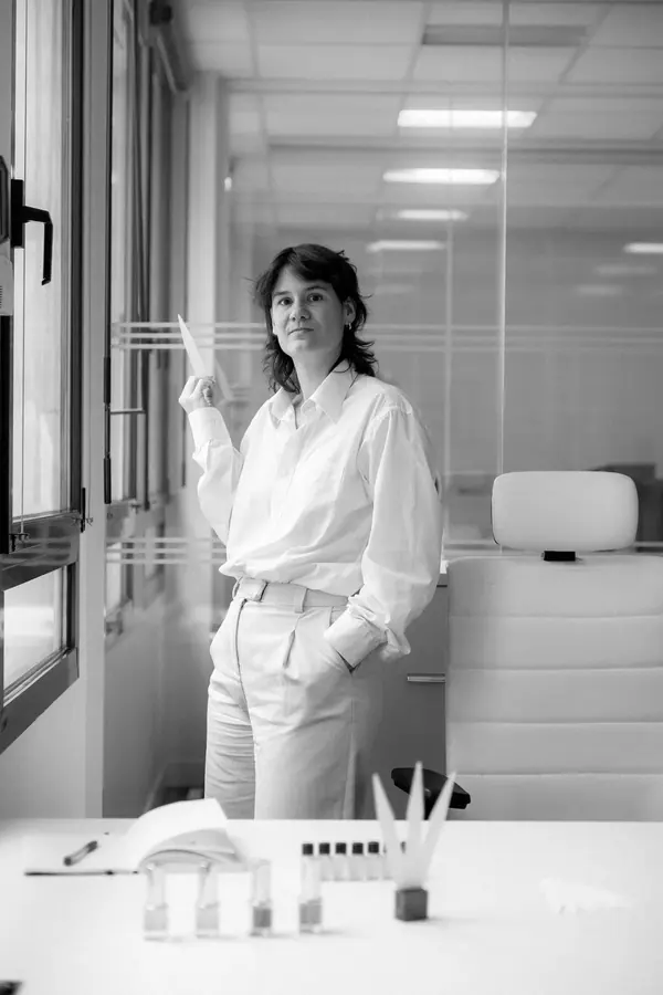 Portrait professionnel d'Agathe, parfumeuse, en chemise blanche dans son laboratoire lumineux, flacons sur la paillasse