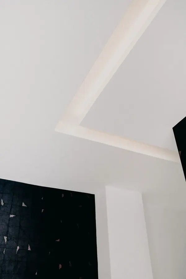 Photographie d'architecture intérieure d'un cabinet dentaire, plafond à éclairage indirect et mur noir texturé