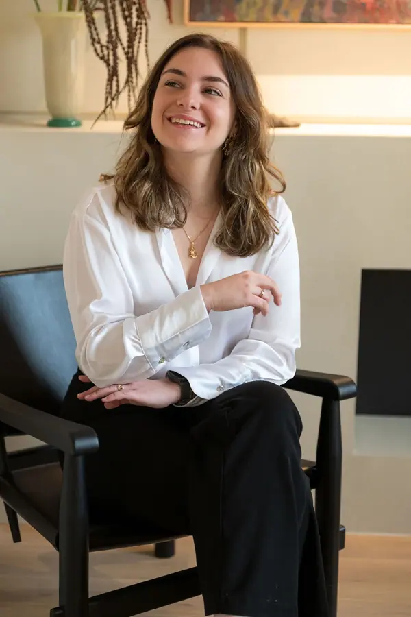 Portrait corporate d'une collaboratrice en chemise blanche assise dans un fauteuil, agence parisienne