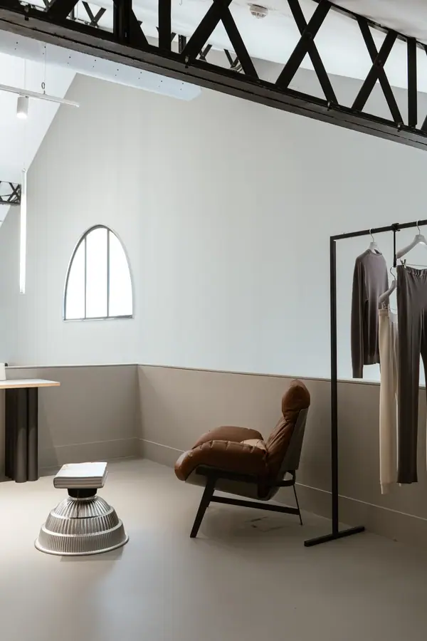 Photographie d'architecture intérieure du showroom HModa 126, fauteuil en cuir et portant sous charpente métallique