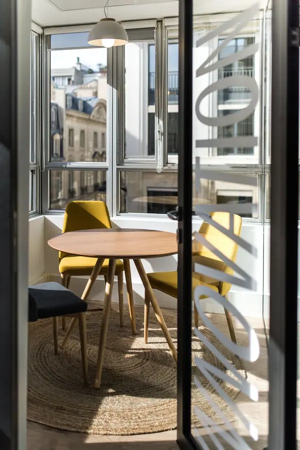 Photographie d'architecture intérieure des bureaux TGS France, salle de réunion vitrée avec table ronde et chaises jaunes