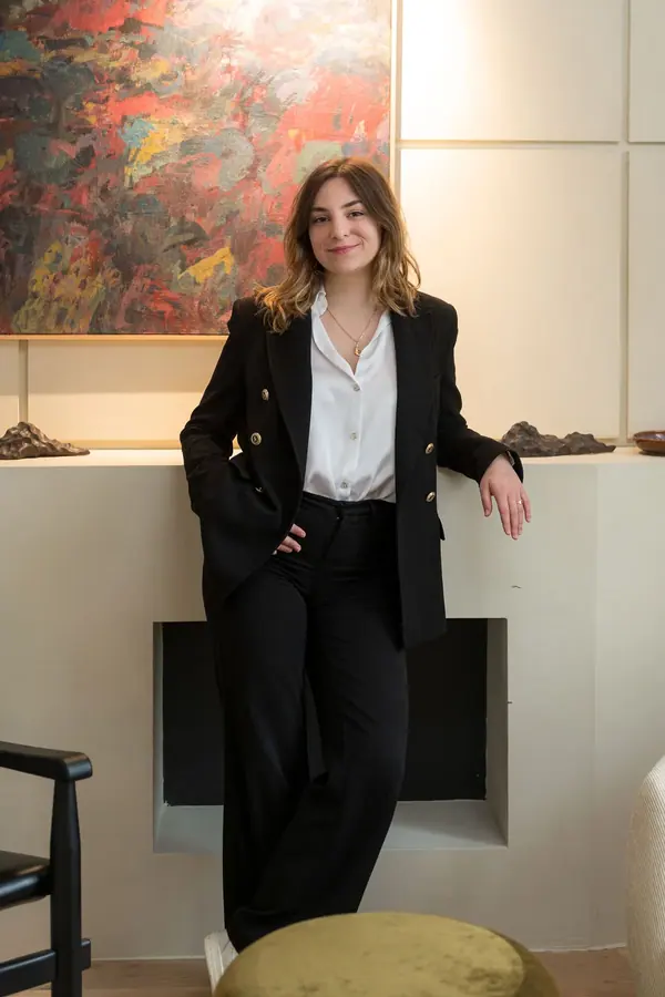 Portrait corporate d'une collaboratrice de The Hoffman Agency debout devant une toile abstraite, lumière douce