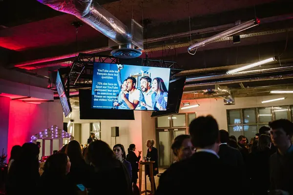 Foule d'invités sous les écrans lors d'une soirée YouTube Google à Paris, reportage photo événementiel