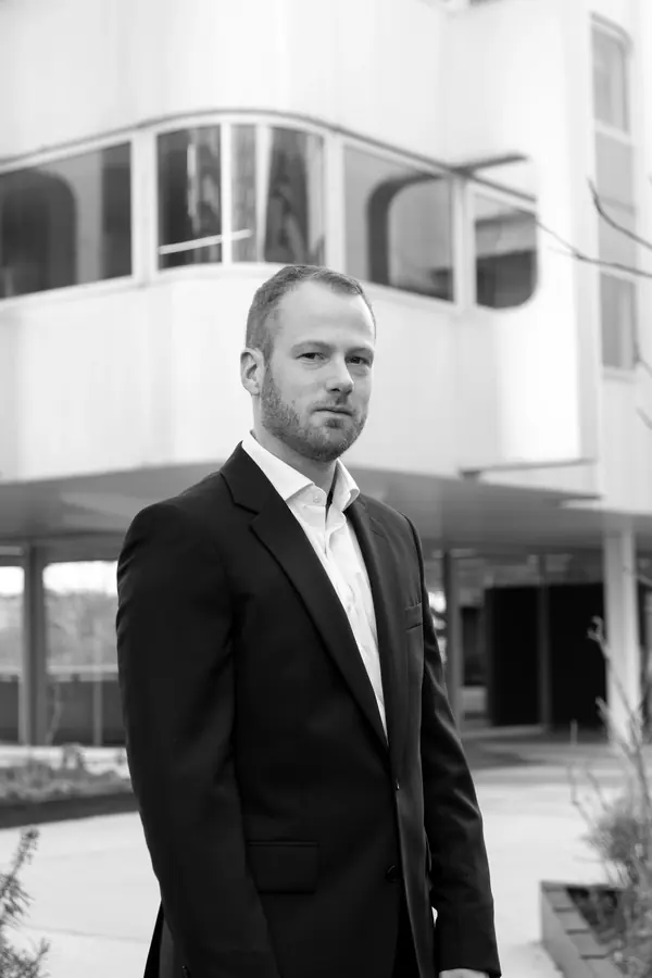 Portrait corporate noir et blanc d'un homme en costume devant un immeuble moderne