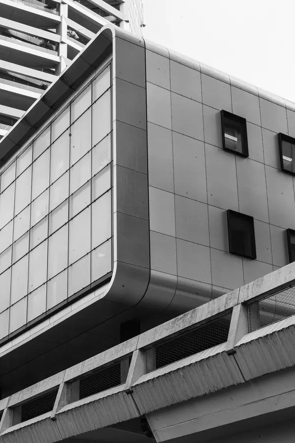 Façade brutaliste en béton aux angles arrondis au-dessus d'une passerelle à Paris, photographie d'architecture noir et blanc