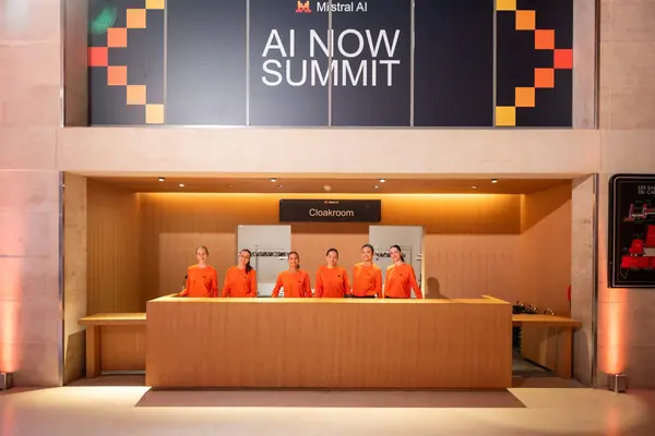 Hôtesses en orange à l'accueil de l'AI Now Summit de Mistral AI à Paris, reportage photo événementiel