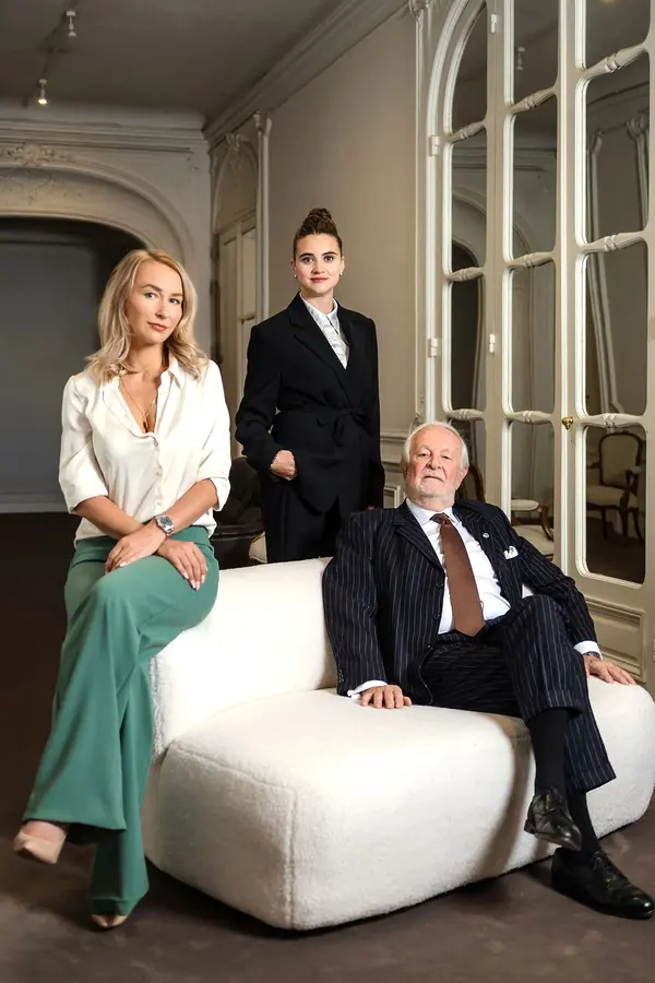 Portrait corporate d'une équipe d'avocats dans un salon à moulures, deux collaboratrices et un associé autour d'un canapé