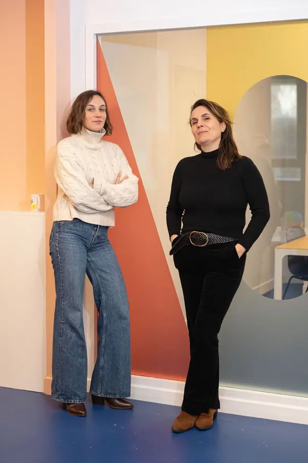 Portrait professionnel de deux formatrices de l'Académie Grandir devant un mur coloré, lumière naturelle
