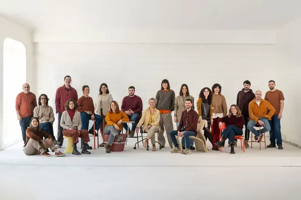 Portrait corporate de groupe de l'équipe Yemanja, une vingtaine de personnes en tons chauds dans un espace blanc
