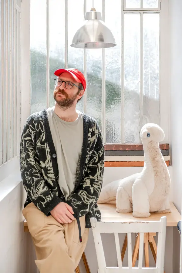 Portrait corporate d'un fondateur de BigStuffed assis près d'une fenêtre, à côté d'une grande peluche blanche