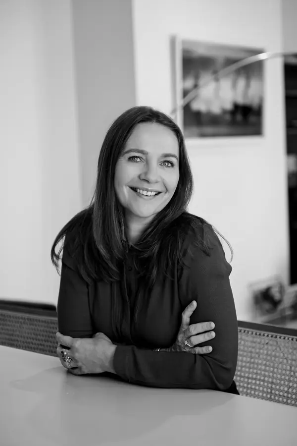 Portrait noir et blanc d'une avocate souriante accoudée à son bureau, photographe portrait avocat Paris