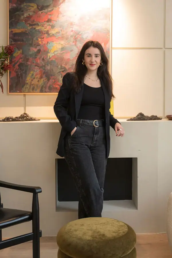 Portrait corporate d'une collaboratrice de The Hoffman Agency debout devant une toile abstraite, lumière douce