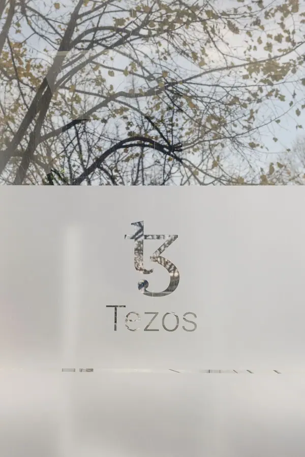 Logo Tezos sur une vitre dépolie à l'entrée des bureaux de Nomadic Labs à Paris, photographie d'architecture intérieure